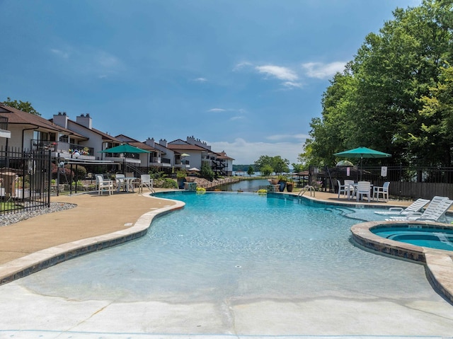 pool with a patio area, a residential view, fence, and a community hot tub