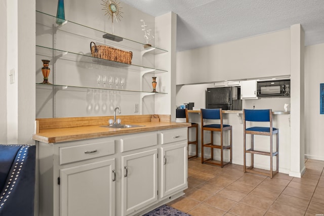 kitchen featuring a textured ceiling, open shelves, a sink, white cabinets, and black appliances