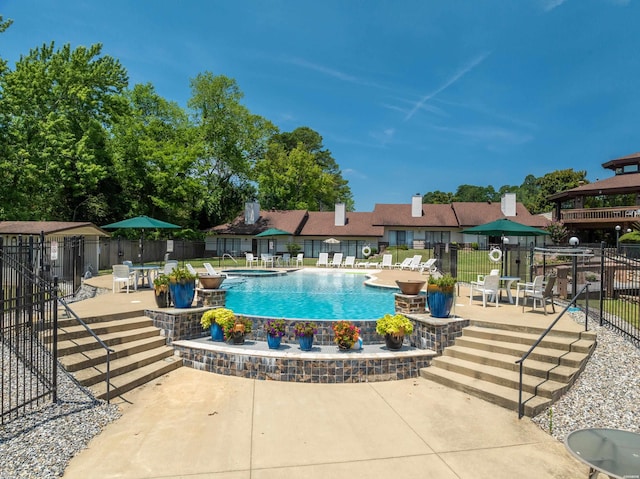 community pool with a patio and fence