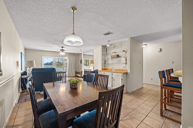 dining area featuring visible vents, a textured ceiling, and light tile patterned flooring