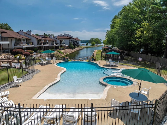 community pool featuring a water view, fence, a hot tub, and a patio