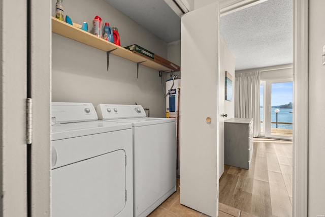 laundry area with a water view, light wood-style flooring, a textured ceiling, washer and dryer, and laundry area