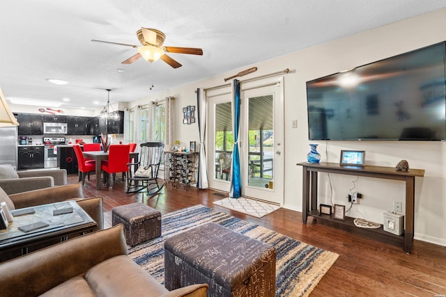 living room featuring ceiling fan, a textured ceiling, baseboards, and dark wood-type flooring