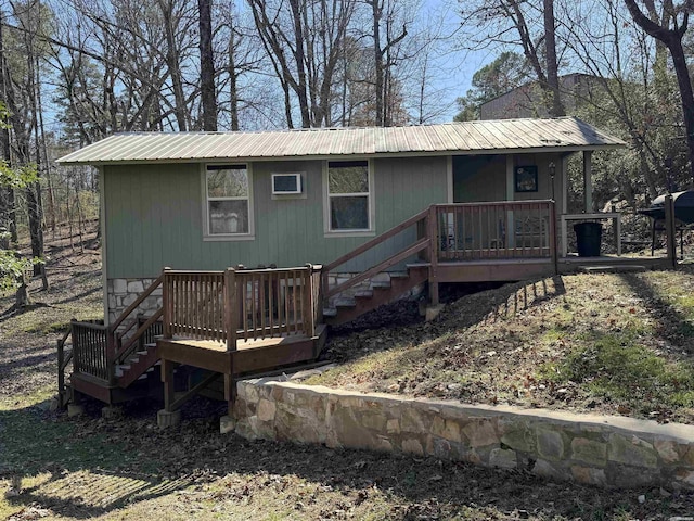 rear view of property with metal roof, covered porch, and stairs