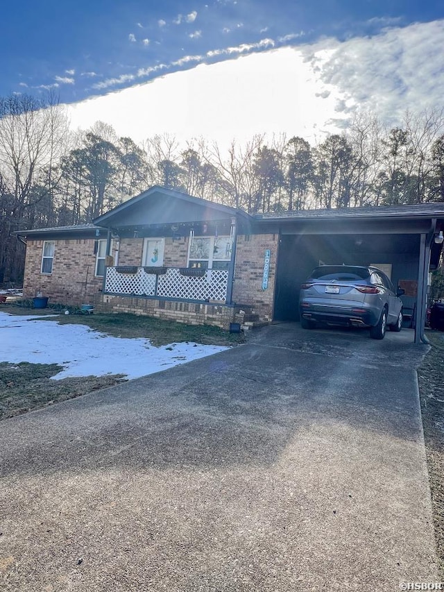 single story home featuring a carport, a porch, concrete driveway, and brick siding