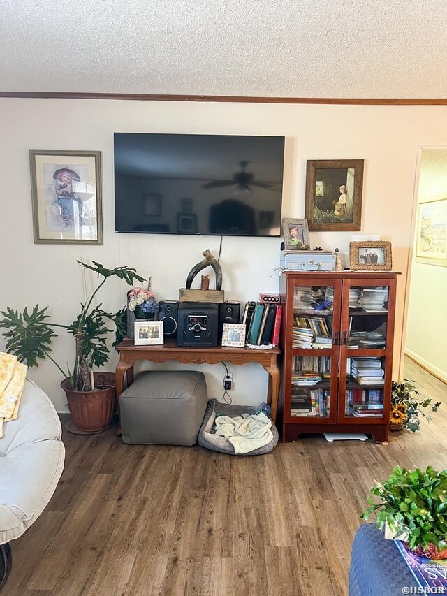 living area featuring crown molding, a textured ceiling, and wood finished floors