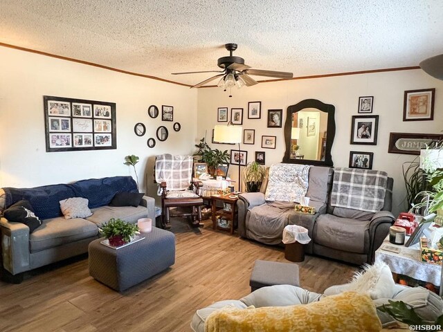 living room with a textured ceiling, ornamental molding, wood finished floors, and a ceiling fan