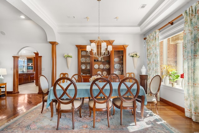 dining room with arched walkways, crown molding, a notable chandelier, decorative columns, and visible vents