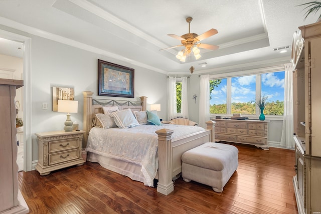 bedroom featuring dark wood-style floors, a raised ceiling, visible vents, and ornamental molding