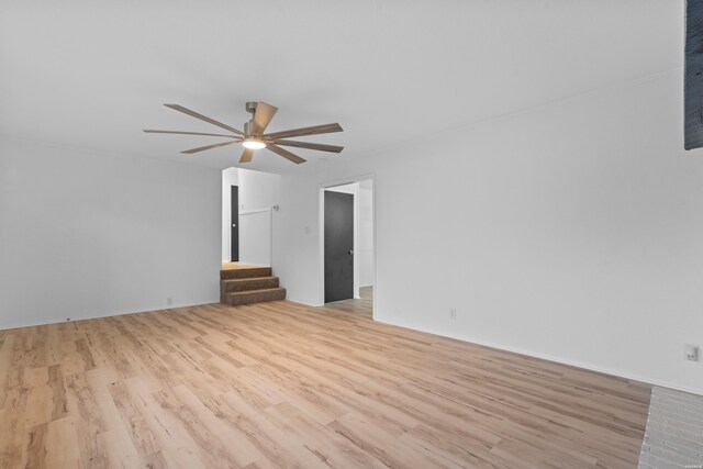 empty room with ceiling fan, stairway, and light wood-style floors