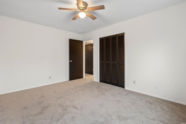 unfurnished bedroom with light carpet, ceiling fan, baseboards, and a closet