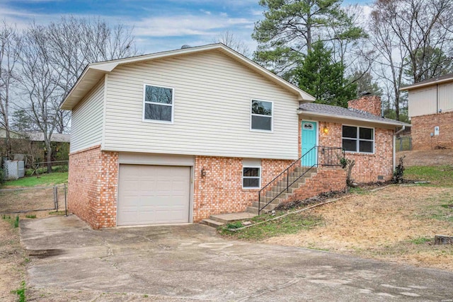 tri-level home featuring brick siding, fence, a chimney, and an attached garage