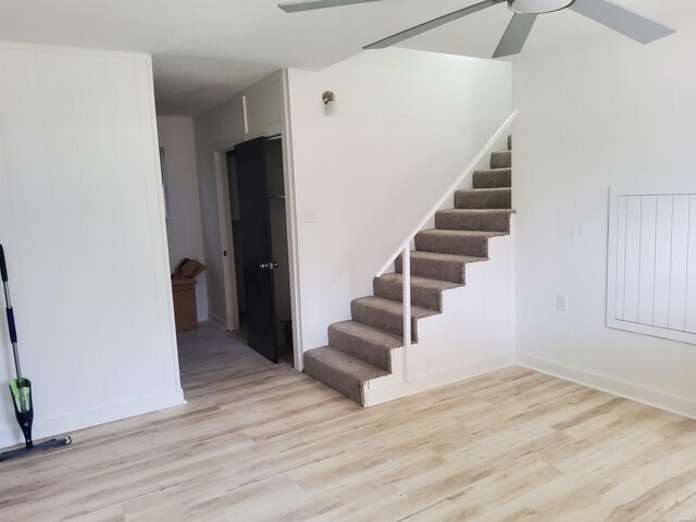 staircase featuring ceiling fan and wood finished floors