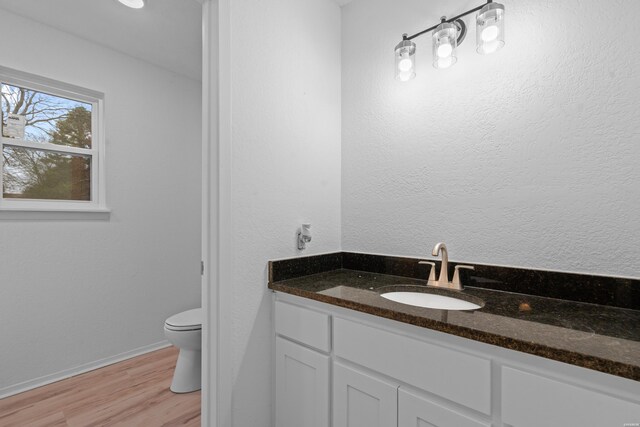 bathroom with toilet, baseboards, wood finished floors, and vanity