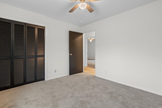 unfurnished bedroom featuring ceiling fan, baseboards, a closet, and light colored carpet