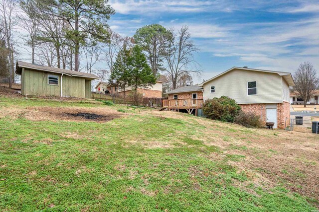 view of yard with fence, a deck, and an outbuilding