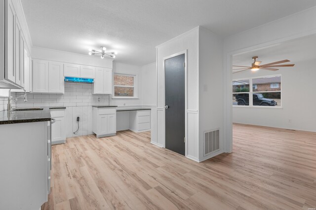 kitchen featuring tasteful backsplash, dark countertops, visible vents, white cabinets, and a sink