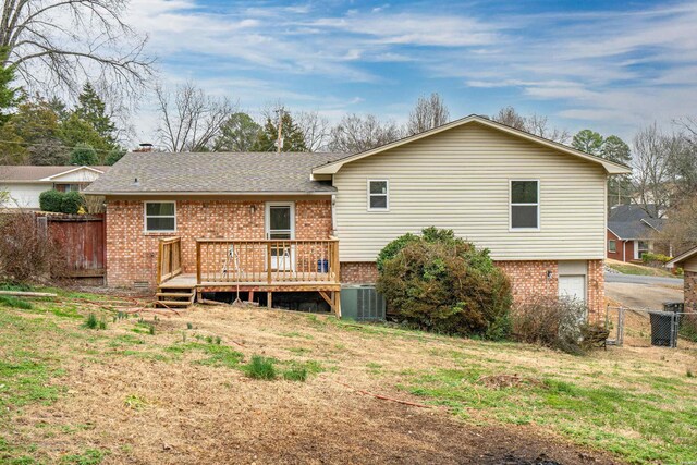 back of house featuring brick siding, fence, central AC, and a wooden deck