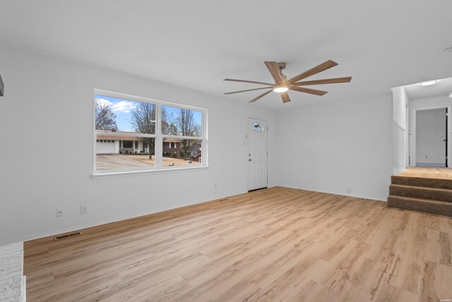 unfurnished living room featuring light wood-type flooring, stairs, visible vents, and a ceiling fan