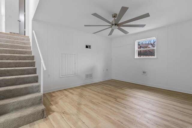 unfurnished living room with visible vents, light wood-style floors, ceiling fan, baseboards, and stairs