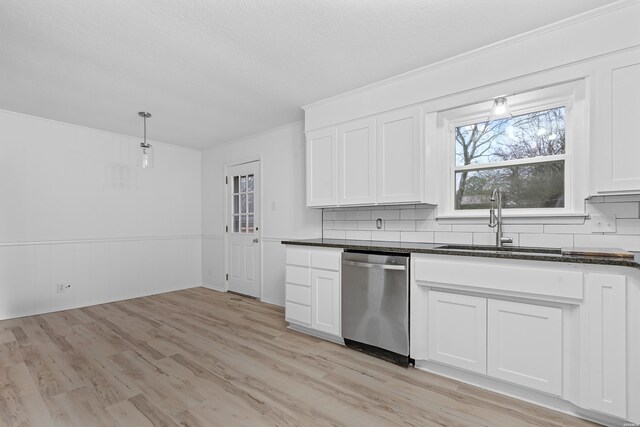 kitchen featuring tasteful backsplash, light wood-style flooring, stainless steel dishwasher, white cabinetry, and a sink