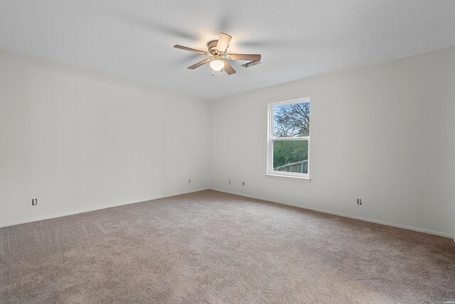 carpeted empty room with ceiling fan and baseboards