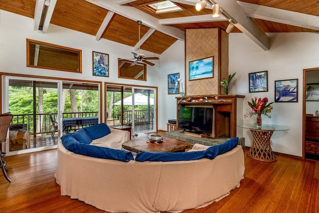 living room with ceiling fan, wood ceiling, a skylight, beamed ceiling, and hardwood / wood-style flooring