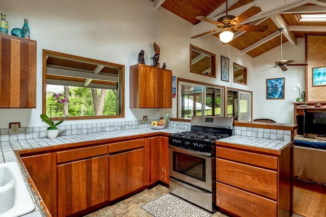 kitchen featuring wood ceiling, stainless steel range with gas cooktop, ceiling fan, and beamed ceiling