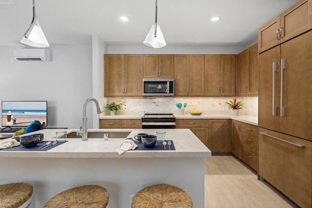 kitchen featuring appliances with stainless steel finishes, backsplash, a kitchen bar, and decorative light fixtures