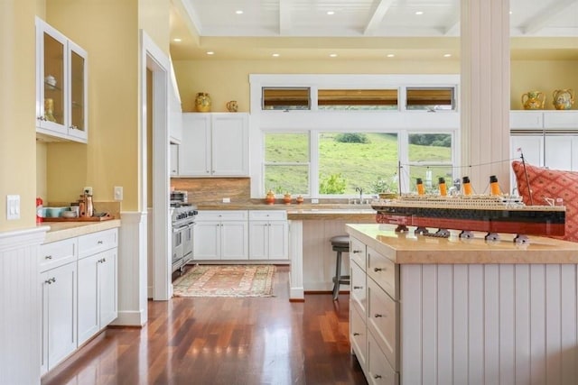 kitchen featuring dark wood finished floors, backsplash, glass insert cabinets, white cabinetry, and beamed ceiling