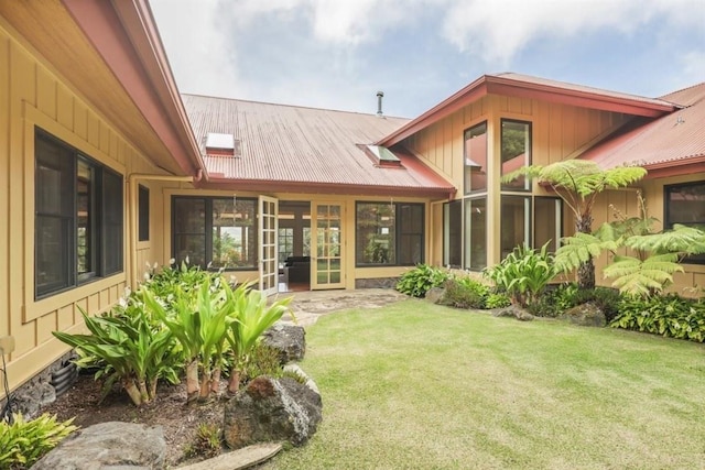 rear view of property featuring metal roof, a lawn, and french doors