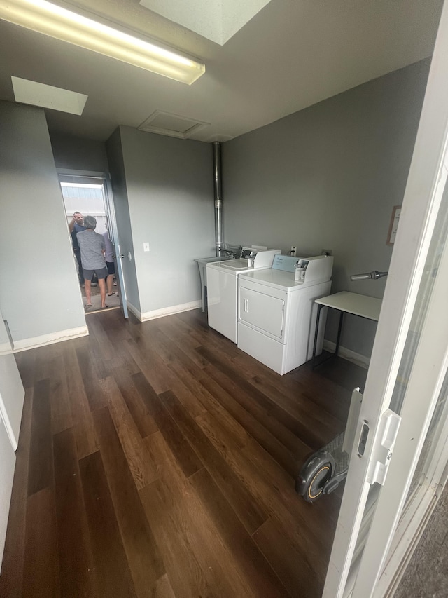 clothes washing area featuring dark wood-style floors, attic access, baseboards, and washing machine and clothes dryer