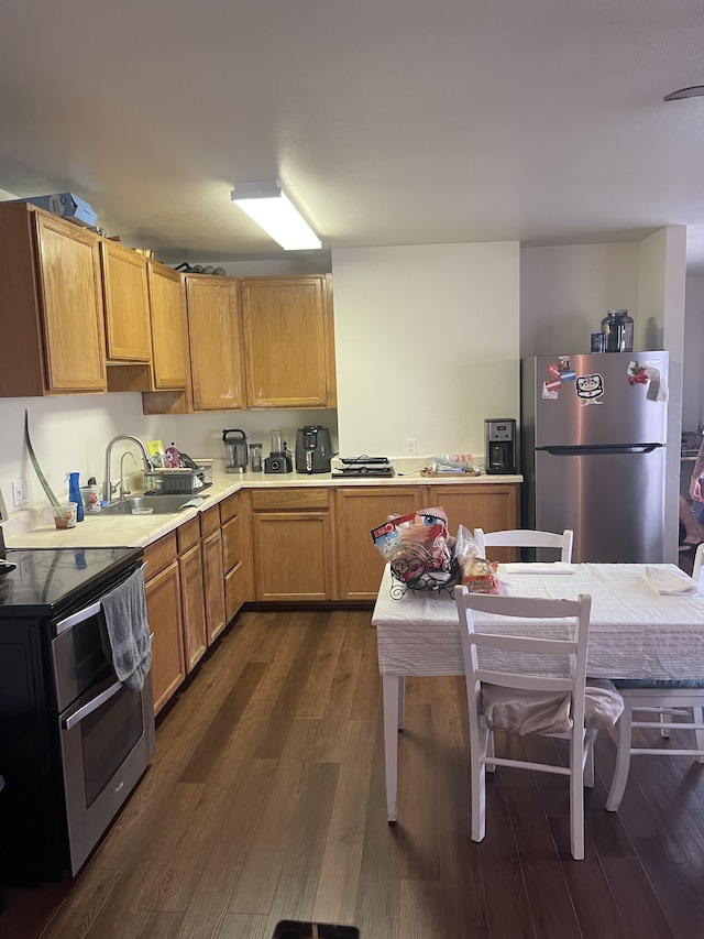 kitchen with stainless steel appliances, light countertops, a sink, and dark wood-style floors