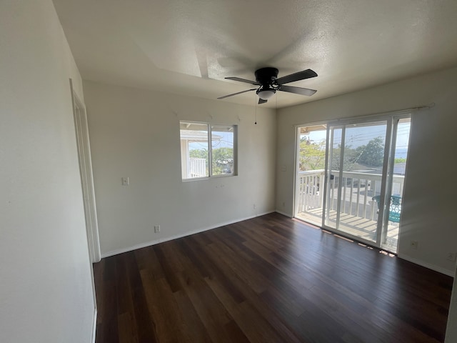 empty room featuring dark wood-type flooring, baseboards, and a ceiling fan