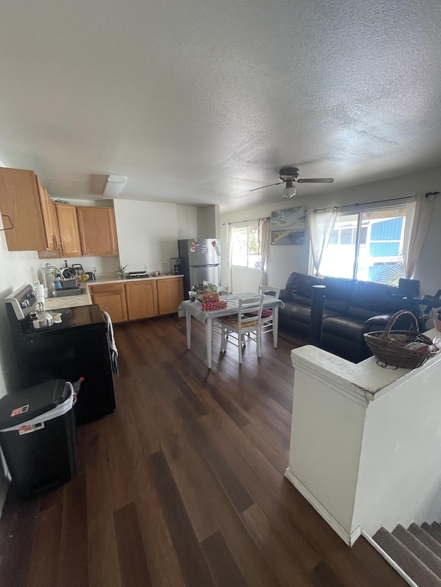 living room featuring dark wood-type flooring, a textured ceiling, and ceiling fan