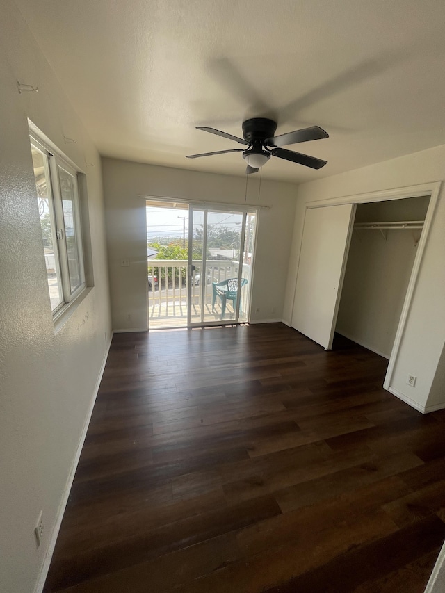 unfurnished bedroom featuring access to outside, ceiling fan, dark wood-type flooring, a closet, and baseboards