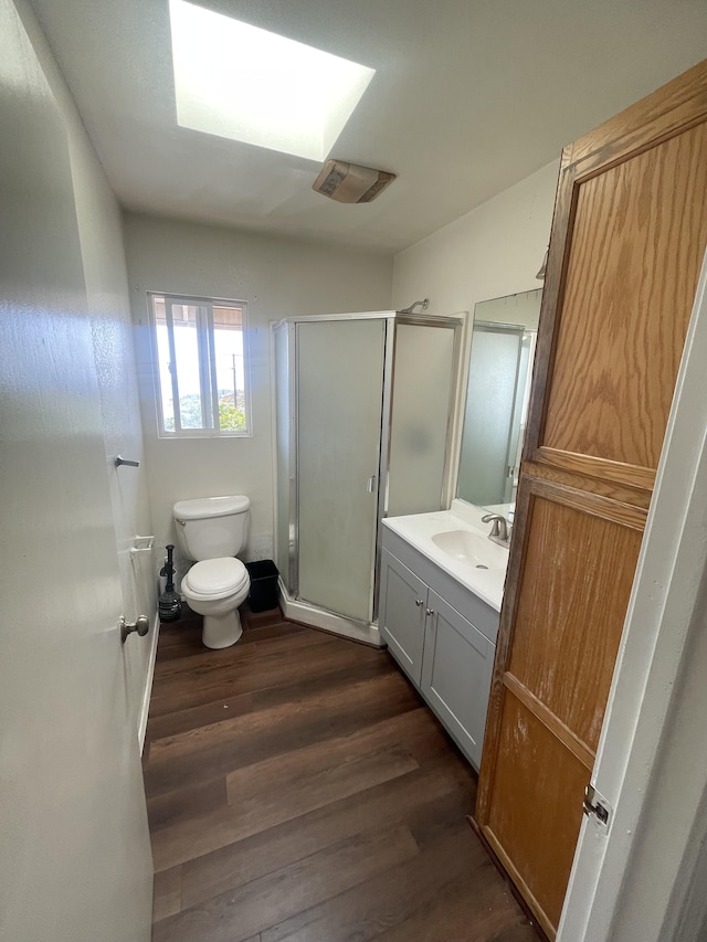 bathroom with toilet, a shower stall, vanity, and wood finished floors