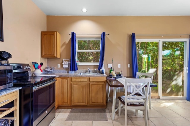 kitchen featuring light tile floors, appliances with stainless steel finishes, light stone counters, and sink