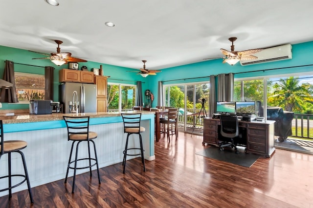 kitchen with stainless steel fridge, ceiling fan, dark hardwood / wood-style flooring, a breakfast bar area, and a wealth of natural light