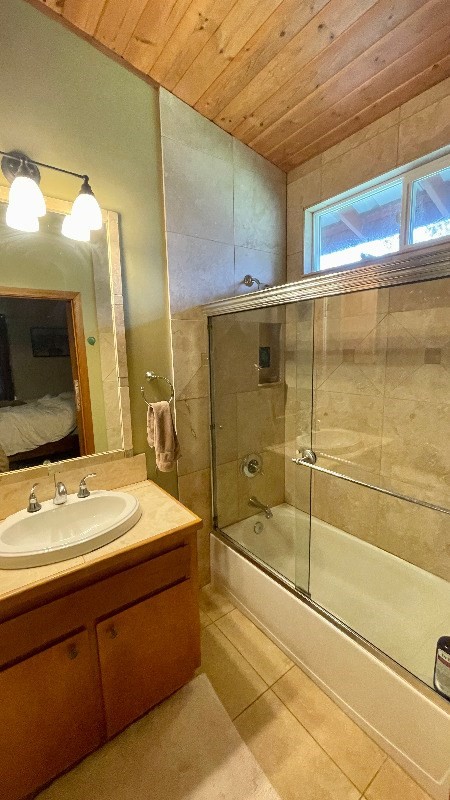 bathroom with wooden ceiling, shower / bath combination with glass door, tile flooring, and vanity with extensive cabinet space