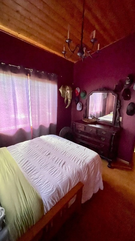 carpeted bedroom featuring a chandelier, wood ceiling, and vaulted ceiling