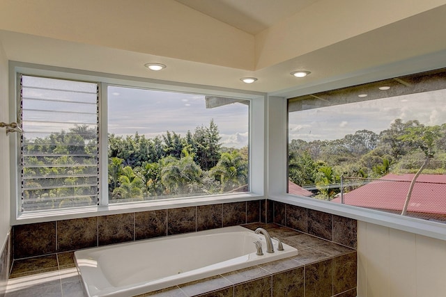 bathroom featuring a relaxing tiled bath and lofted ceiling