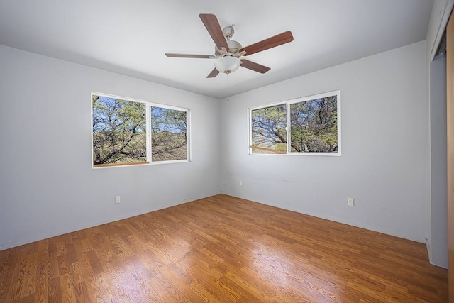 unfurnished room featuring hardwood / wood-style floors, a healthy amount of sunlight, and ceiling fan