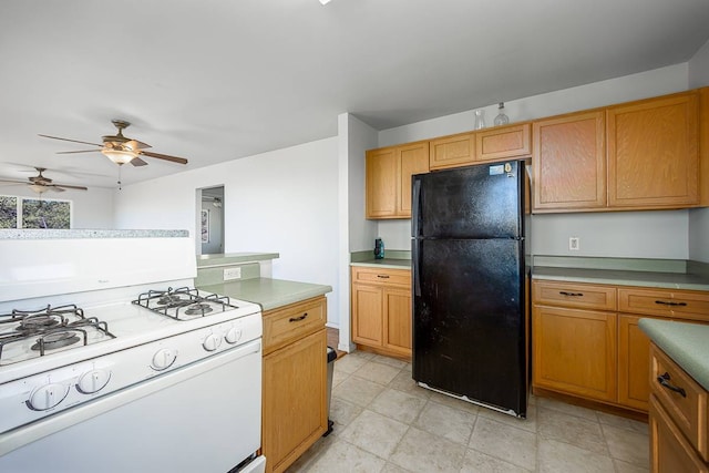 kitchen with white range oven, light tile floors, black refrigerator, and ceiling fan