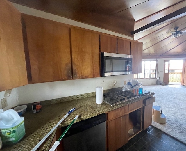 kitchen with dark colored carpet, stainless steel appliances, ceiling fan, and dark stone countertops