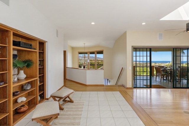 entrance foyer featuring a skylight, ceiling fan with notable chandelier, and light hardwood / wood-style flooring