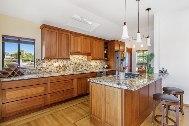 kitchen with tasteful backsplash, light hardwood / wood-style floors, appliances with stainless steel finishes, and a wealth of natural light