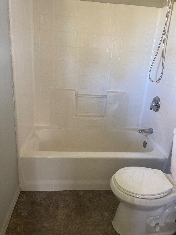 bathroom featuring tiled shower / bath combo and toilet