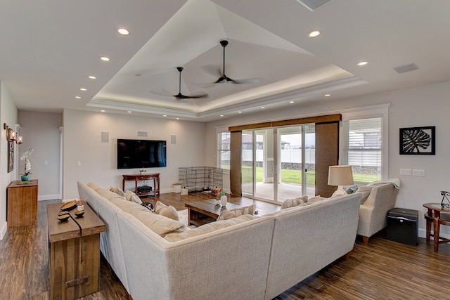 living room with dark hardwood / wood-style flooring, ceiling fan, and a tray ceiling