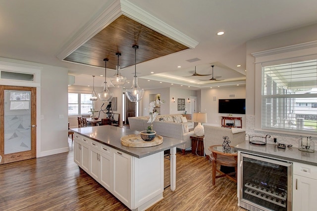 kitchen featuring wine cooler, pendant lighting, dark wood-type flooring, a tray ceiling, and white cabinetry